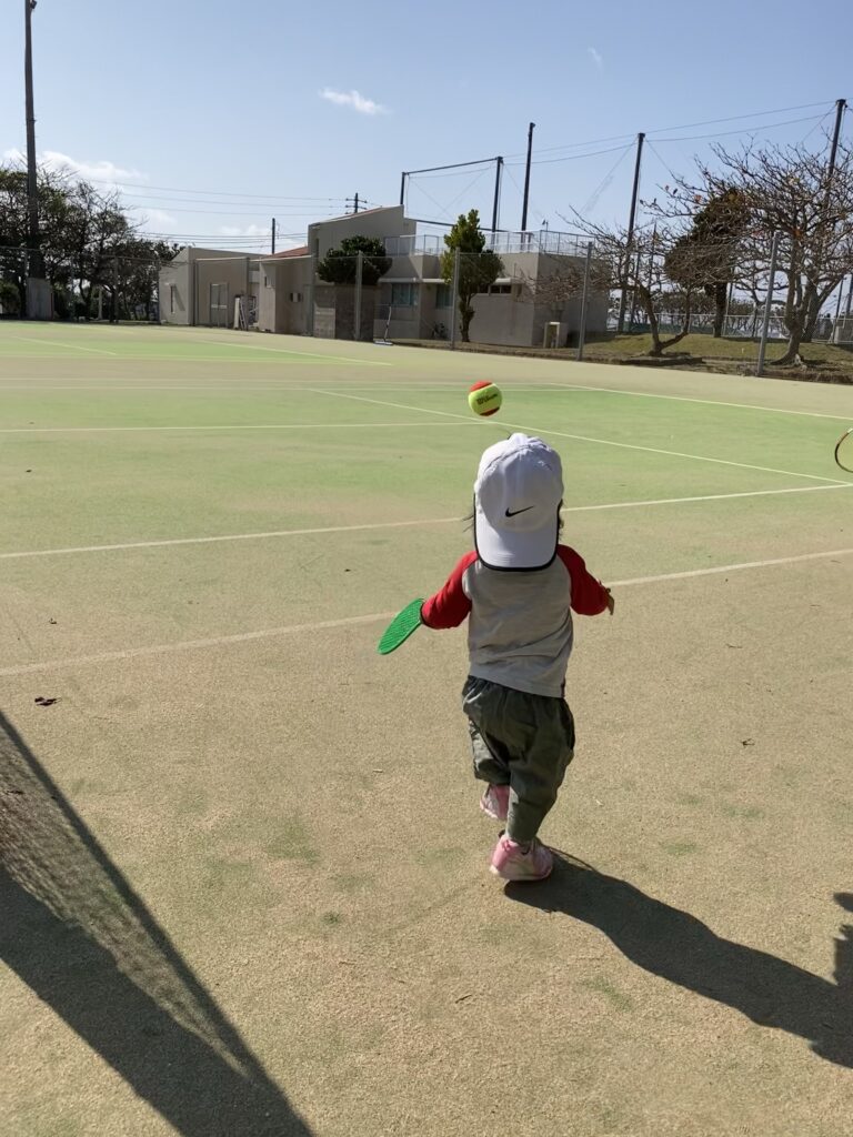 テニスボールを追いかける子供の後ろ姿